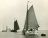 Achteraanzicht op een witgeschilderde tjalk Seven Bells met kajuit zeilend op open water onder de vlag van de KNZ & RV (Collectie ANWB/Scheepvaartmuseum ongedateerd)
